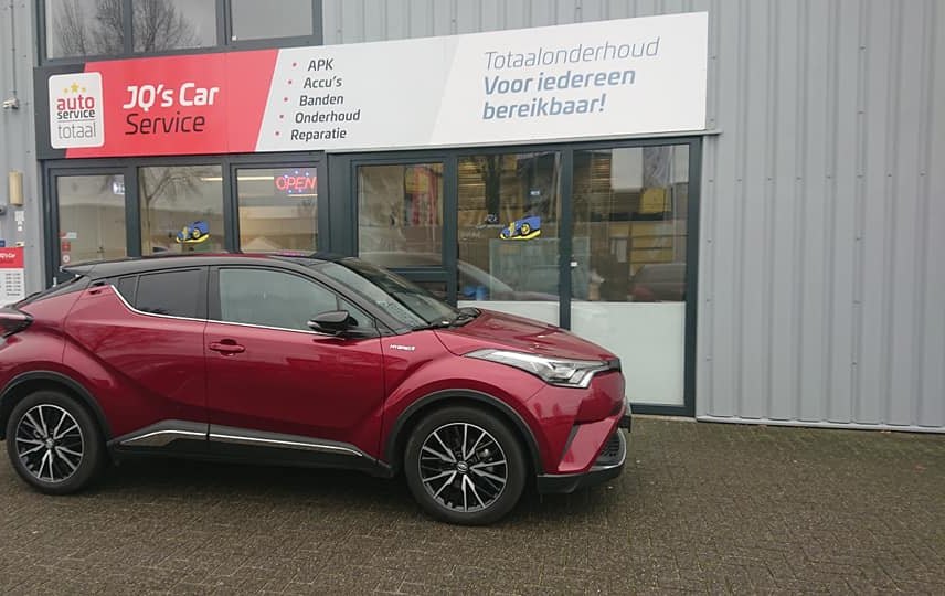 Een rode Toyota C-HR voor de zaak aan het Keizersveld, met de hot-rod op het raam